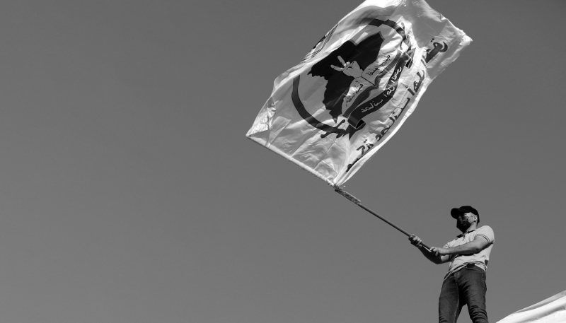 Un partisan du groupe militant Asaïb Ahl al-Haq, ou Ligue des vertueux, porte son drapeau lors d'une manifestation près de l'entrée de la zone verte dans le centre de Bagdad, en Irak, le 14 juillet 2023. 