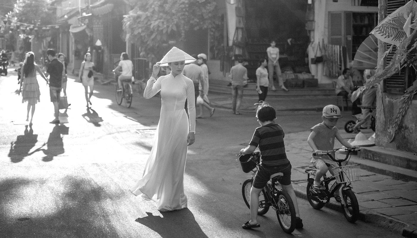 Femme portant le traditionnel áo dài dans une rue de la vieille ville de Hoi An, Vietnam.
