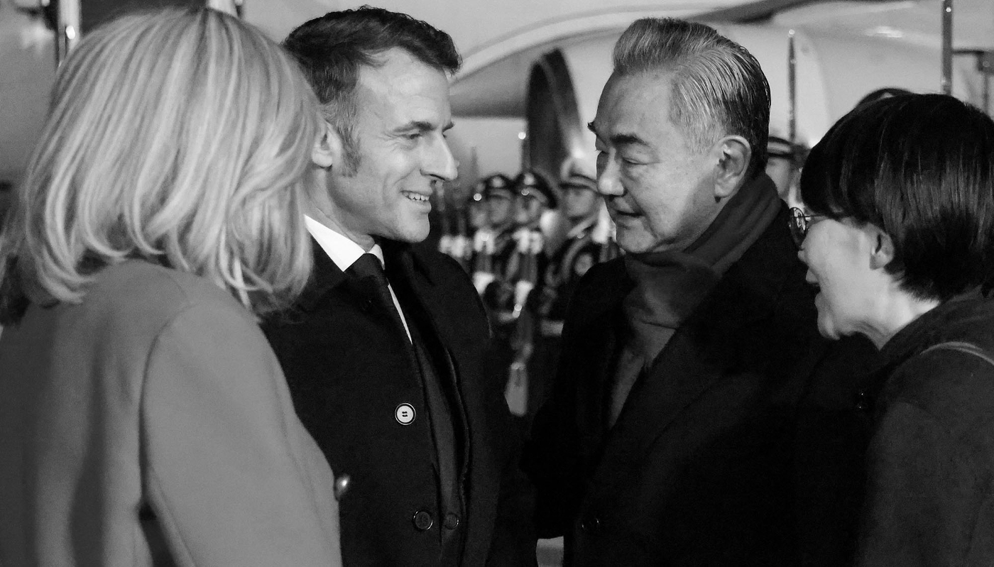 Le ministre chinois des affaires étrangères Wang Yi accueille le président français Emmanuel Macron et son épouse Brigitte Macron à l'aéroport international de Pékin, le 3 décembre 2025.